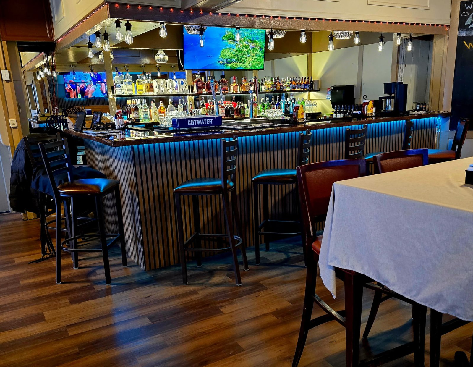 Bar stools lined up along the slatted wood bar at Vista Lounge under blue accent lighting