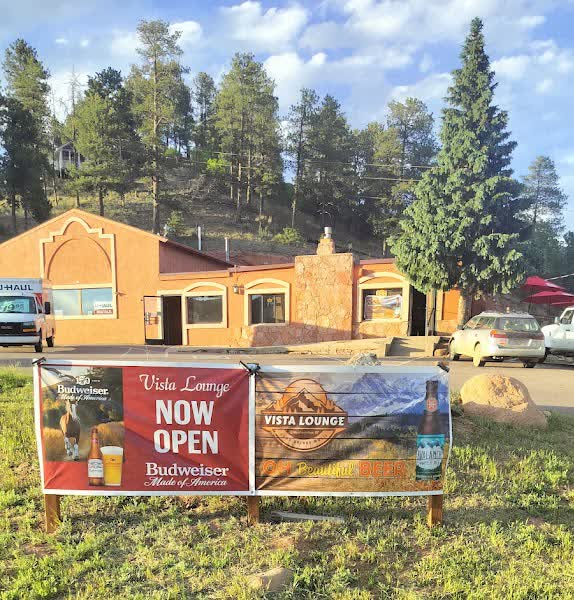 Vista Lounge Now Open banner in front of the adobe-style building on Highway 24 in Woodland Park